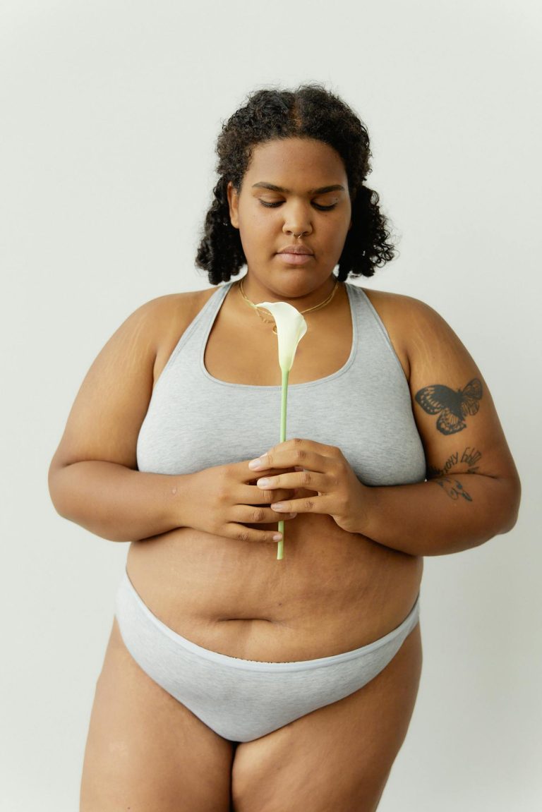 Portrait of a woman in underwear holding a calla lily, embracing body positivity.
